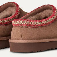 Brown slippers with red trim on a white background