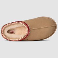 Tan UGG slipper with red trim on a light gray background