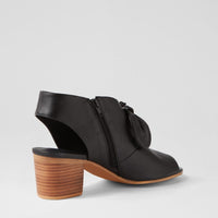 Black heeled shoe with a wooden sole on a light gray background