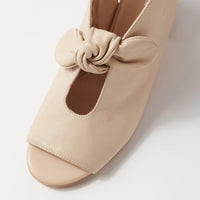 Beige shoe with a knot detail on a light gray background