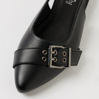 A close-up of a black leather pointed-toe pump with a decorative strap and silver-tone buckle detail across the vamp, shown on a light gray background.