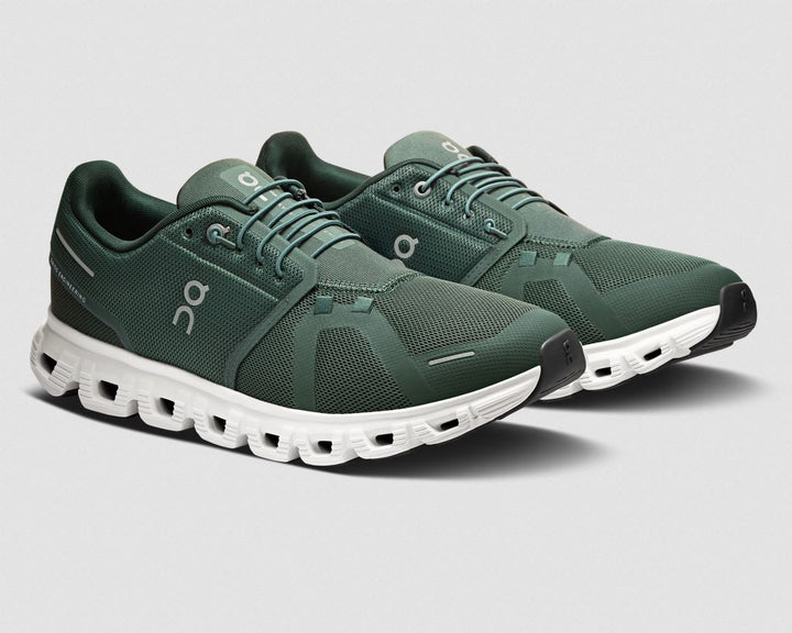 Green running shoes with white soles on a light gray background