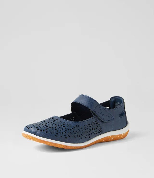 A navy blue Mary Jane-style shoe with perforated detailing on the toe, a hook-and-loop strap, and a white midsole with an orange outsole, shown against a light gray background.
