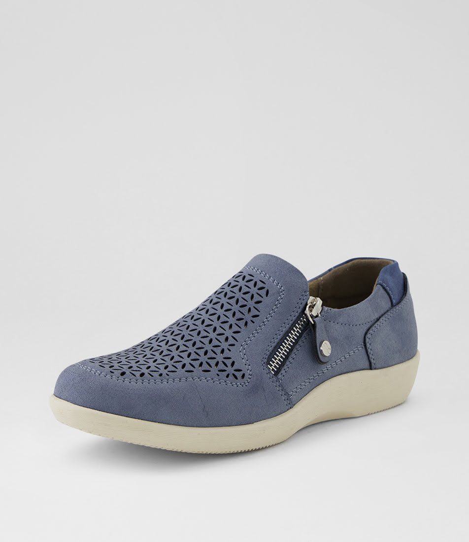 A single slip-on shoe in slate blue suede with geometric laser-cut perforations on the toe, a silver zipper, and a thick cream-colored sole, shown against a light gray background.