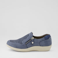 A single slip-on wedge shoe in slate blue suede with a geometric cutout pattern on the toe, a side zipper, and a cream-colored sole, shown against a light gray background.