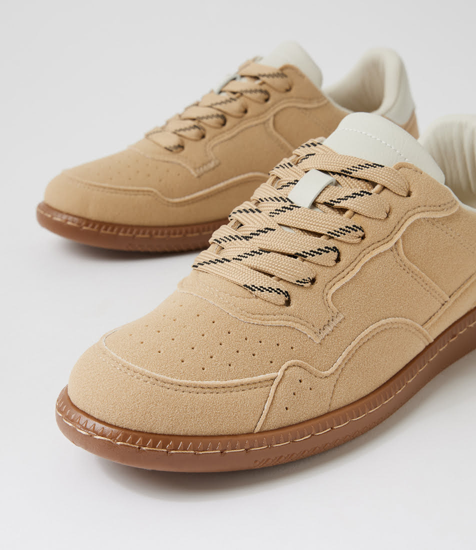 A pair of beige suede low-top sneakers with brown rubber soles and black-and-white patterned laces, shown on a clean white background.