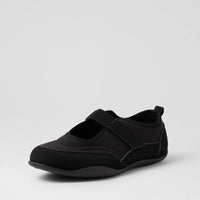 A single black slip-on shoe with a hook-and-loop strap across the top, shown from a three-quarters angle on a light gray studio background.