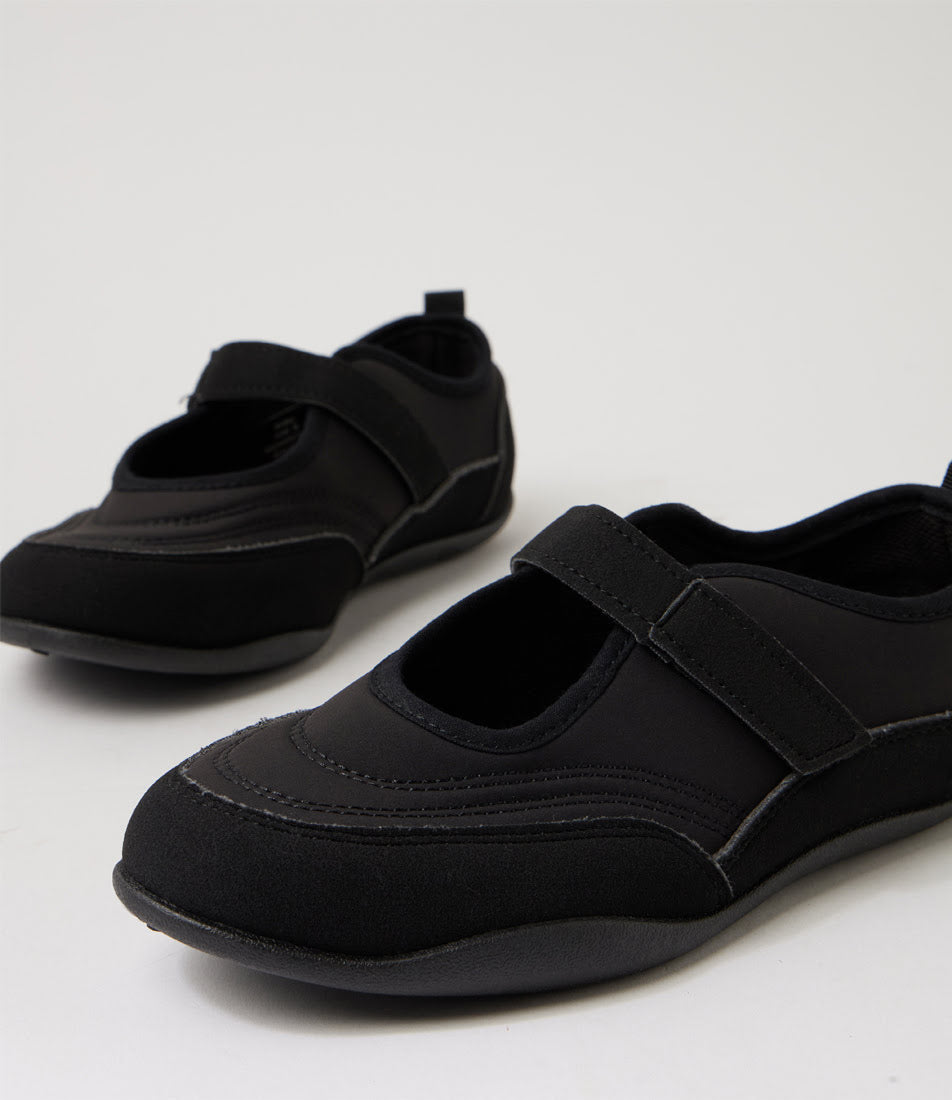 A pair of black Mary Jane-style slip-on shoes with hook-and-loop strap closures, photographed on a clean light gray studio background.