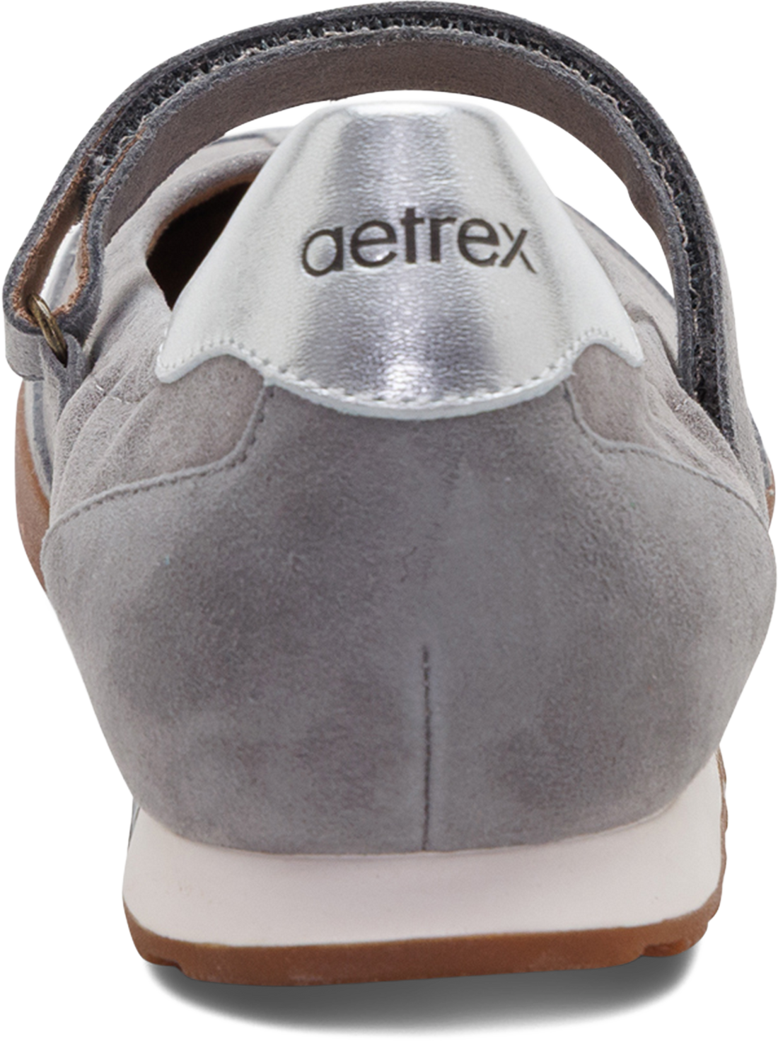 Close-up rear view of a gray suede shoe with a metallic silver heel tab, a dark strap, and the aetrex logo printed on the silver tab.