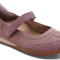 A single women's Mary Jane flat shoe in dusty mauve suede, featuring a hook-and-loop strap closure, a light tan footbed, and a brown outsole, shown on a white background.