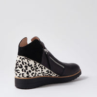 Black wedge shoe with leopard print pattern on a light gray background