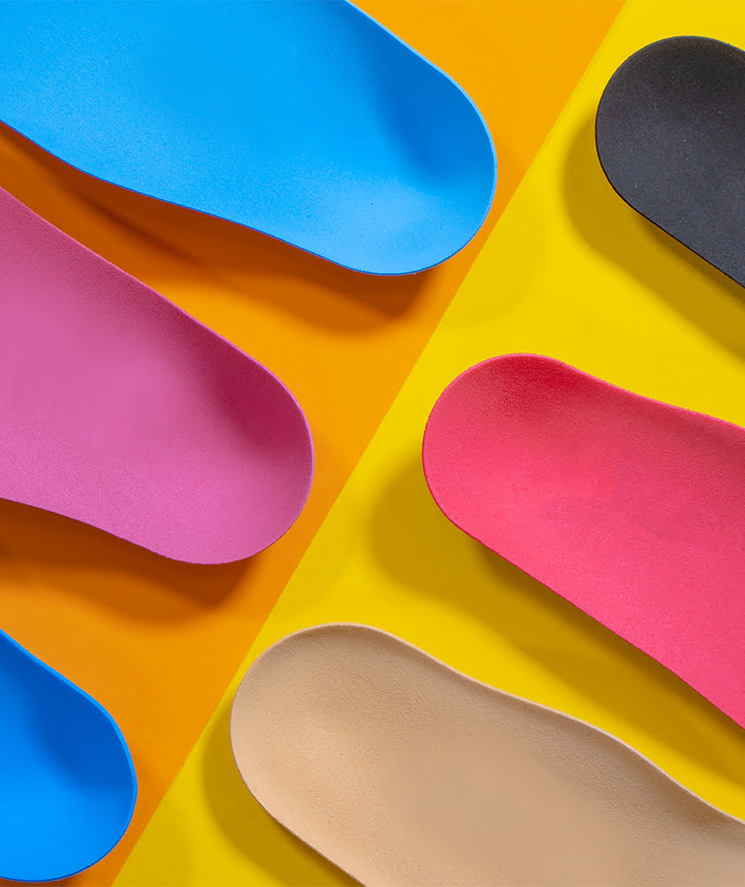Multiple colors and styles on insoles on an orange and yellow table.