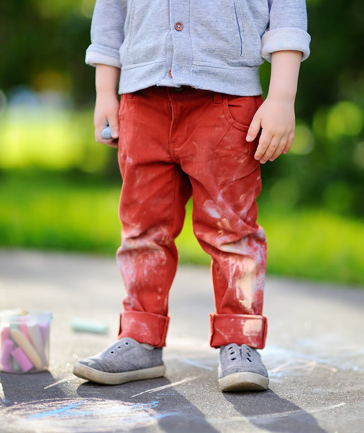 Boy taking a break from doing chalk art, while wearing shoes from Shoe Mill.