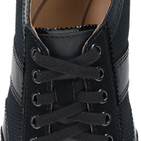 A top-down view of a black leather sneaker with black laces, showcasing the black textured upper, silver eyelets, and a brown insole with the 'danskø' brand logo.